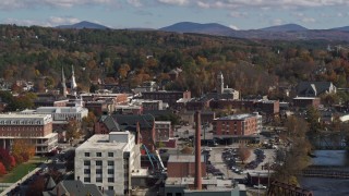 DX0002_218_030 - 5.7K aerial stock footage of a smoke stack and city buildings by the river, Montpelier, Vermont