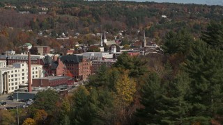DX0002_218_033 - 5.7K aerial stock footage of flying by autumn trees with smoke stack in the background, Montpelier, Vermont