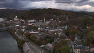 DX0002_220_015 - 5.7K aerial stock footage of the city hall clock tower rising above brick buildings at sunset, Montpelier, Vermont