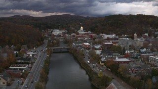 DX0002_220_017 - 5.7K aerial stock footage of flying by a bridge on the river with a view of the state capitol at sunset, Montpelier, Vermont