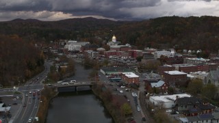 DX0002_220_023 - 5.7K aerial stock footage reverse view of the state capitol at sunset while flying away from a bridge over the river, Montpelier, Vermont