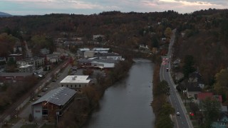 DX0002_220_037 - 5.7K aerial stock footage of flying over the river and Berlin Street to approach grocery store at sunset, Montpelier, Vermont