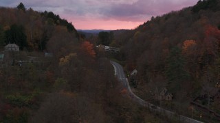 DX0002_220_042 - 5.7K aerial stock footage of a road between hills with colorful trees at sunset, Montpelier, Vermont
