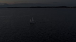 DX0002_225_035 - 5.7K aerial stock footage of a sailboat on Lake Champlain at twilight, Burlington, Vermont