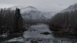 DX0002_227_001 - 5.7K aerial stock footage of flying low over the river toward snowy mountains in Leavenworth, Washington