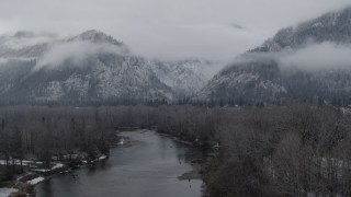 DX0002_227_002 - 5.7K aerial stock footage of ascending away from the river and snowy mountains in Leavenworth, Washington