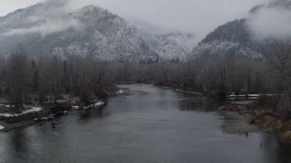 DX0002_227_014 - 5.7K aerial stock footage of following the river to approach snowy mountains in Leavenworth, Washington