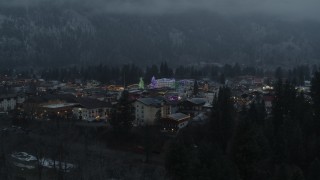 DX0002_227_050 - 5.7K aerial stock footage ascend from trees to reveal a small town decorated with Christmas trees and lights, Leavenworth, Washington