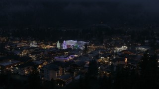 DX0002_228_014 - 5.7K aerial stock footage ascend to reveal town with Christmas trees and lights at night in Leavenworth, Washington