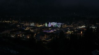 DX0002_228_021 - 5.7K aerial stock footage ascend from trees to reveal Christmas trees and lights at night, Leavenworth, Washington