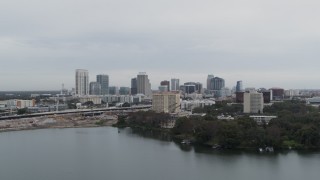 DX0003_233_007 - 5.7K aerial stock footage ascend from lake near hotel for view of the city's skyline, Downtown Orlando, Florida