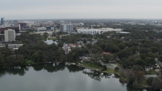 DX0003_233_020 - 5.7K aerial stock footage descend toward lakeside park while focused on apartment buildings in Orlando, Florida