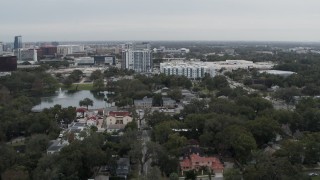 DX0003_233_021 - 5.7K aerial stock footage descend toward lakeside park while focused on apartment buildings in Orlando, Florida