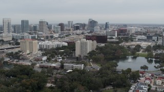 DX0003_233_022 - 5.7K aerial stock footage orbit office building by a lake, with city's skyline in the background, Downtown Orlando, Florida