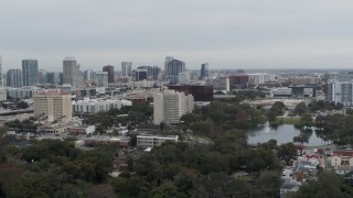 DX0003_233_024 - 5.7K aerial stock footage ascend from lake toward office building and city's skyline, Downtown Orlando, Florida