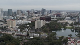 DX0003_233_025 - 5.7K aerial stock footage flying away from lake, office building and city's skyline, Downtown Orlando, Florida