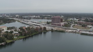 DX0003_233_026 - 5.7K aerial stock footage of light freeway traffic and office building by a lake in Orlando, Florida
