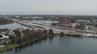 DX0003_233_027 - 5.7K aerial stock footage of flying by light freeway traffic and office building by a lake in Orlando, Florida