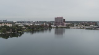DX0003_233_029 - 5.7K aerial stock footage descend by lake while focused on office building by light freeway traffic, Orlando, Florida