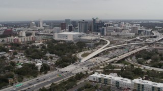 DX0003_234_004 - 5.7K aerial stock footage of flying by Amway Center, city skyline beside freeway interchange, Downtown Orlando, Florida