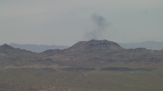 FG0001_000054 - 4K aerial stock footage of smoke rising from behind a Mojave Desert mountain in San Bernardino County, California