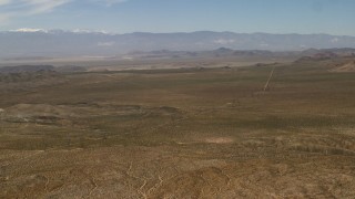 FG0001_000104 - 4K aerial stock footage pan across desert plain and road to reveal Iron Ridge in the Mojave Desert, San Bernardino County, California