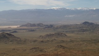 FG0001_000114 - 4K aerial stock footage of the San Bernardino Mountains with snow behind Mojave Desert mountains, San Bernardino County, California