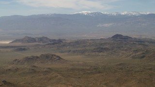 FG0001_000115 - 4K aerial stock footage of a view of the San Bernardino Mountains with snow from Mojave Desert mountains, San Bernardino County, California