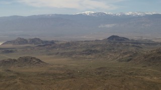 FG0001_000116 - 4K aerial stock footage of a view of snowy San Bernardino Mountains from Mojave Desert mountains, San Bernardino County, California