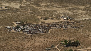 FG0001_000122 - 4K aerial stock footage of passing an auto junkyard in the Mojave Desert, San Bernardino County, California