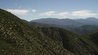 FG0001_000159 - 4K aerial stock footage pan across and fly over steep green mountain slope in the San Gabriel Mountains, California