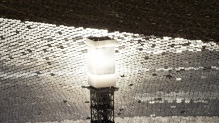 FG0001_000209 - 4K aerial stock footage of a close-up view and orbit of a glowing power tower boiler at the Ivanpah Solar Electric Generating System in California