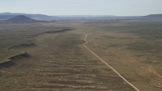 FG0001_000239 - 4K aerial stock footage flyby a mesa and road through desert plain in the Arizona Desert