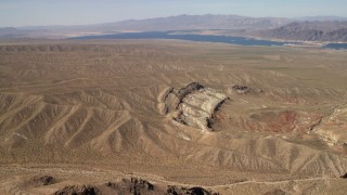 FG0001_000264 - 4K aerial stock footage approach a scarred hillside with Lake Mead in the background, Nevada Desert