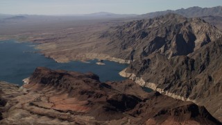 FG0001_000288 - 4K aerial stock footage of flying by barren mountains overlooking the shore of Lake Mead, Nevada