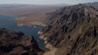FG0001_000289 - 4K aerial stock footage of flying by barren mountains beside the shore of Lake Mead, Nevada