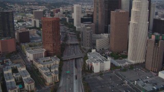 HDA06_67 - HD stock footage aerial video tilt from a bird's eye view of the 110 freeway to reveal skyscrapers in Downtown Los Angeles, California, twilight
