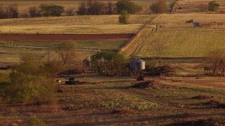 HDA12_136 - HD stock footage aerial video of a barn, silos, equipment beside a country road at sunset in Oklahoma
