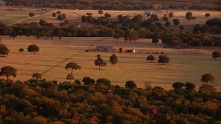HDA12_153 - HD aerial stock footage video of worn barns and farm fields at sunset in Nocona, Texas