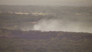HDA12_167 - HD stock footage aerial video of fire trucks near smoke rising from trees at sunset in Texas