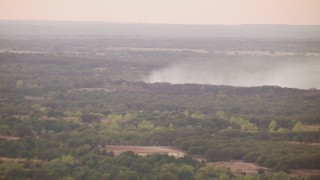 HDA12_168 - HD stock footage aerial video of smoke rising from trees at sunset and zoom to wider view, Texas