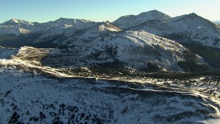 HDA13_444 - HD stock footage aerial video fly over a ridge and pan to a mountain road at sunrise, Rocky Mountains, Colorado