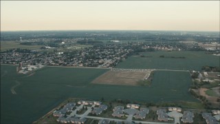 PP001_008 - HD aerial stock footage of flying over fields to approach homes at sunset in Homer Glen, Illinois