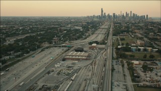 PP001_021 - HD aerial stock footage fly over train yard by freeway to approach Downtown Chicago, Illinois at sunset