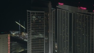 PP003_036 - HD stock footage aerial video of flying by a hotel and casino to reveal rides on Steel Pier at night, Atlantic City, New Jersey