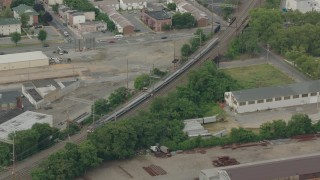 PP003_114 - HD stock footage aerial video track a commuter train passing industrial buildings in Wilmington, Delaware