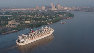 PVED01_013 - 4K aerial stock footage of Carnival Cruise ship sailing Mississippi River, reveal Downtown New Orleans at sunrise, Louisiana