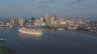 PVED01_031 - 4K aerial stock footage of a Carnival Cruise ship on the river by Downtown New Orleans at sunrise, Louisiana