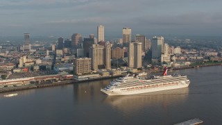 PVED01_037 - 4K aerial stock footage orbit a Carnival Cruise ship sailing by Downtown New Orleans at sunrise, Louisiana