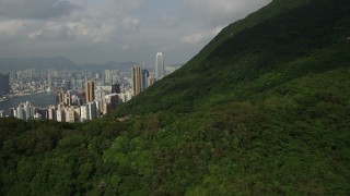 SS01_0034 - 5K stock footage aerial video fly over forest mountain and tilt to reveal skyscrapers on Hong Kong Island, China